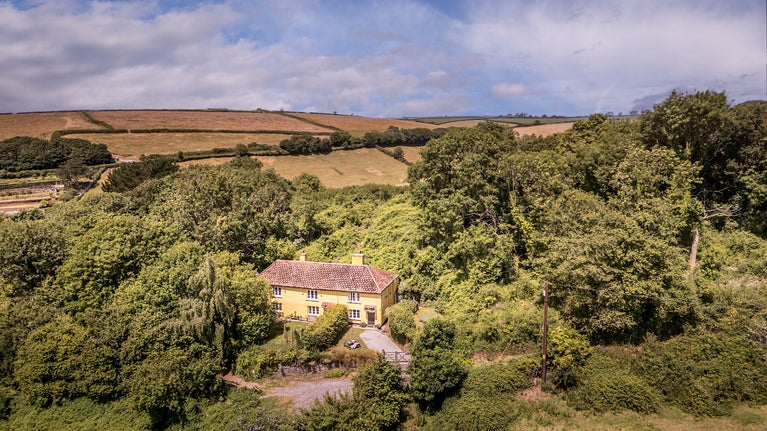 An aerial view of Crockers Cottage and the surrounding woodland and fields, Devon